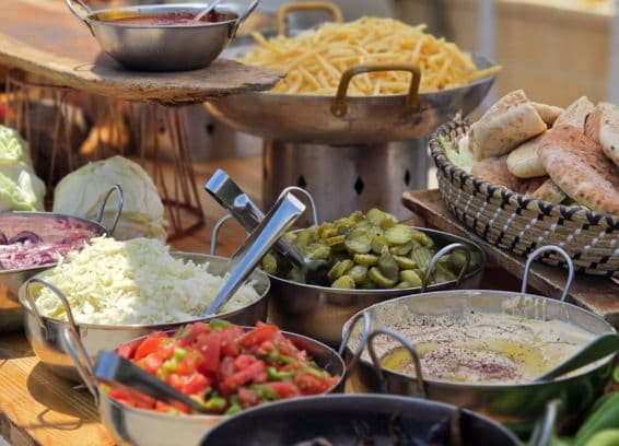 שולחן דוכן מזון: צ'יפס, פיתות, חמוצים, חומוס וסלטים קצוצים